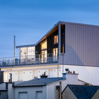 Photographie au crépuscule d'une surélévation en bois sur une copropriété à Brest. Photographie intégrée au dossier de retour d'expérience, réalisé par BATYLAB en mars 2023. Crédits : Pascal LEOPOLD, Photographe.