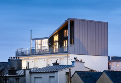 Photographie au crépuscule d'une surélévation en bois sur une copropriété à Brest. Photographie intégrée au dossier de retour d'expérience, réalisé par BATYLAB en mars 2023. Crédits : Pascal LEOPOLD, Photographe.